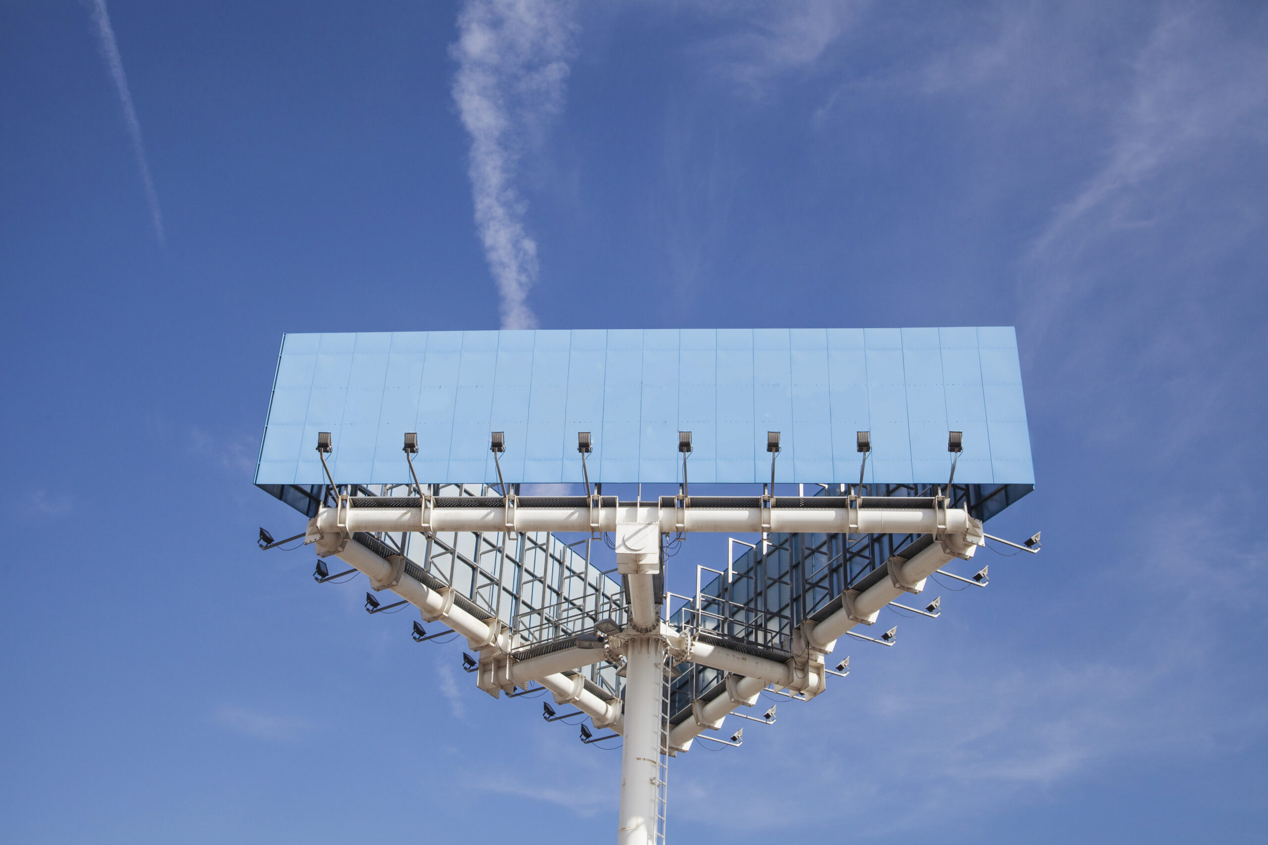 low angle view blue big hoarding pole with light against blue sky scaled - Techkeymonk