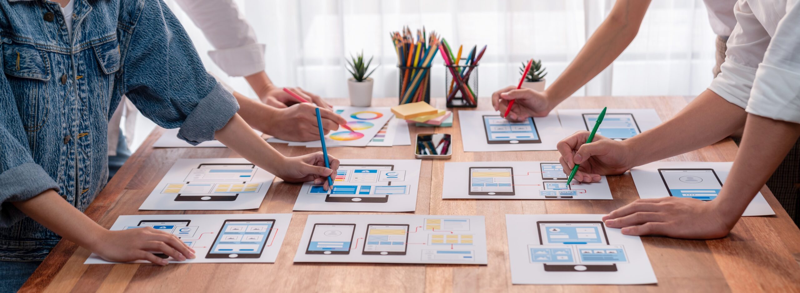 panorama shot frontend developer team brainstorming ui ux designs mobile app paper wireframe interface user interface development team planning userfriendly ui design scrutinize scaled - Techkeymonk